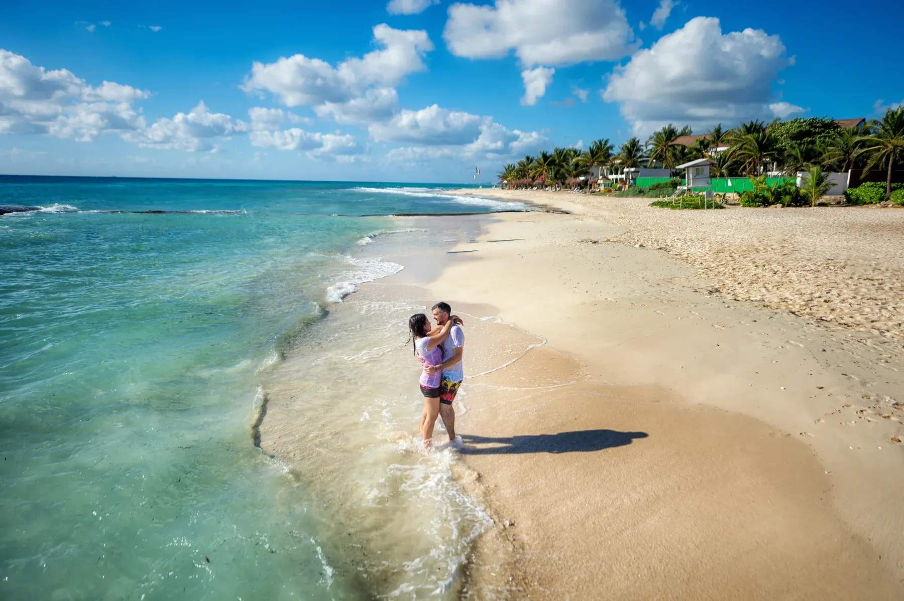 Empty turquoise beach in Costa Rica, a couple walking small along the water's edge